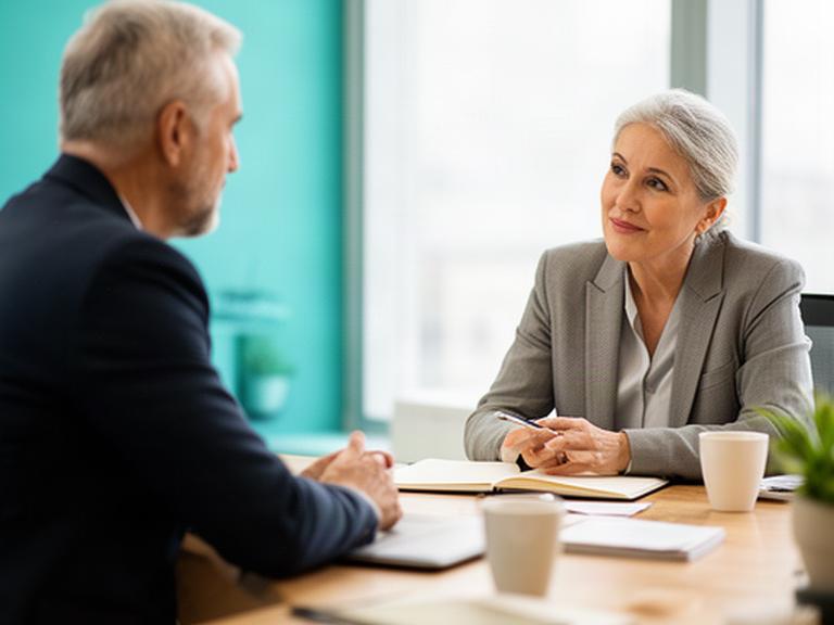 Senior HR consultant listening to a business owner during a bright office meeting